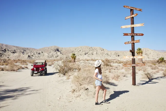 A women exploring the San Andreas Fault with a parked jeep off to the side.